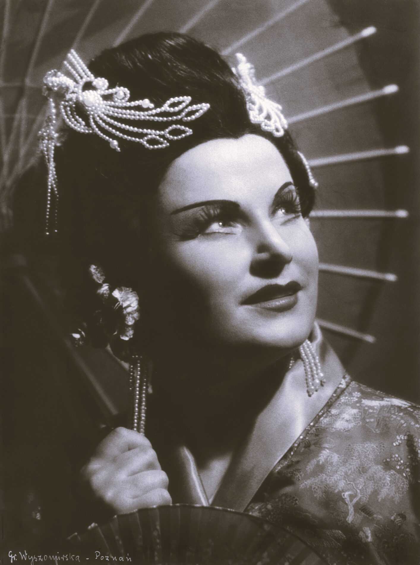 Vilma Bukovec v vlogi Čo-čo-san v operi Madame Butterfly. V rokah drži sončnik in pahljačo, oblečena pa je v kimono.